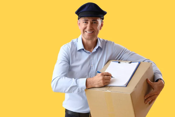 Mature Postman Clipboard Parcel Yellow Background — Stock Photo, Image
