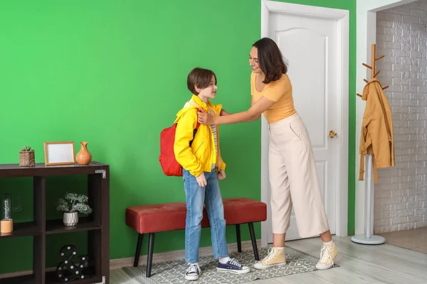 Anne oğlunu koridorda okula hazırlıyor.