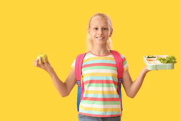 Glückliches Mädchen Mit Rucksack Lunchbox Und Frischem Apfel Auf Gelbem — Stockfoto