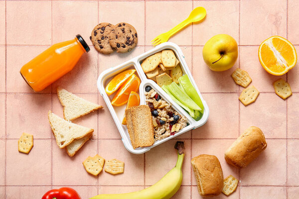 Lunchbox with delicious food and bottle of juice on orange tile background