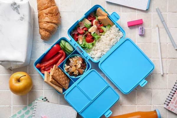 用米色瓷砖做的带有美味食物和不同文具的午餐盒 — 图库照片