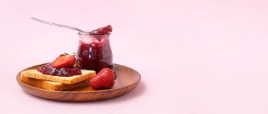 Lezzetli tost tabağı ve pembe arka planda çilek reçeli.