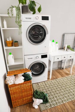 Çamaşır odasının içinde çamaşır makinesi, masa ve sepet var.