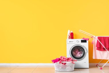 Çamaşır odasında kirli çamaşır, çamaşır makinesi ve kurutma makinesi olan sepet.