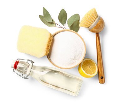 Beyaz arka planda bir kase kabartma tozu, sirke, temizlik fırçası, sünger ve limon.