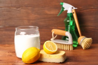 Kavanoz dolusu kabartma tozu, limon ve ahşap arka planda temizlik malzemeleri.