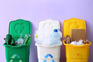 Leylak arka planında farklı türde çöp konteynırları. Geri dönüşüm kavramı