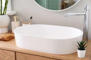 Masada banyo aksesuarları olan beyaz lavabo.