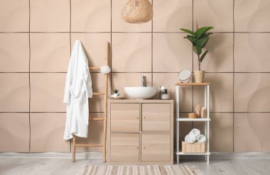 Bornozlu, lavabolu ve ahşap dolaplı banyo aksesuarları.