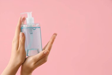 Pembe arka planda sıvı sabun olan eller