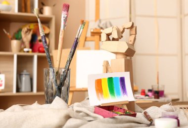 Sanatçının stüdyosunda fırçalar, boyalar ve mini sehpalar.