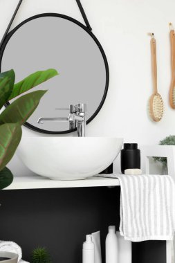 Lavabo, sabun, havlu ve banyo aksesuarları banyodaki raflarda.