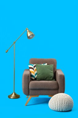 Koltuk, puf ve lamba mavi arkaplanda.