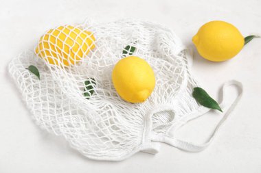 Beyaz arka planda taze limonlu ağ torbası, yakın plan.
