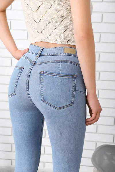 Jonge Vrouw Stijlvolle Jeans Bij Lichte Bakstenen Muur Achteraanzicht — Stockfoto