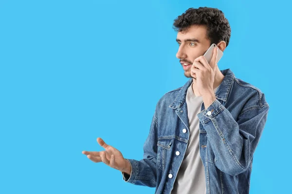 Όμορφος Νεαρός Μιλάει Από Κινητό Τηλέφωνο Μπλε Φόντο — Φωτογραφία Αρχείου