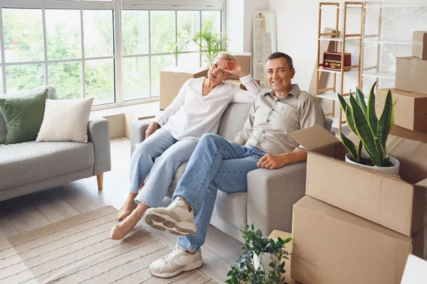 Tired mature couple sitting in room on moving day