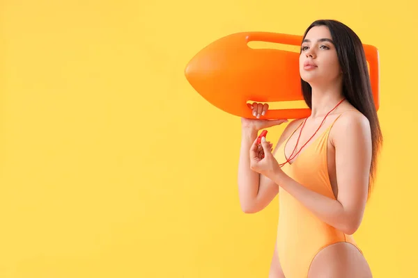 Female lifeguard with board and whistle on yellow background