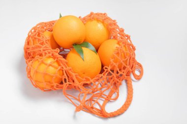 Beyaz arka planda taze portakallı ağ torbası