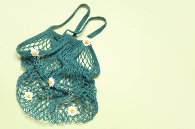 Bej arkaplanda papatya çiçekleri olan ağ torbası.