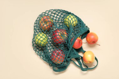 Bej arkaplan üzerinde taze elmalar olan ağ torbası.