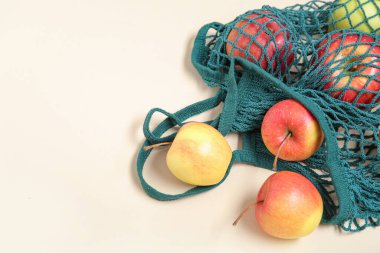 Bej arkaplanlı taze elmalı ağ torbası, yakın plan.