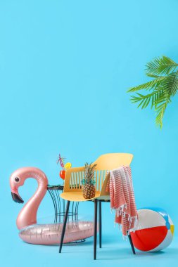 Sandalyeli, ananaslı, plaj aksesuarlı ve mavi arkaplanlı bir kokteyl. Yaz tatili kavramı