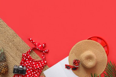 Kamera, ananas ve kırmızı arka planda plaj aksesuarları olan bir kase çilek. Yaz tatili kavramı