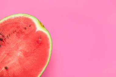 Pembe arka planda olgun karpuzun yarısı.