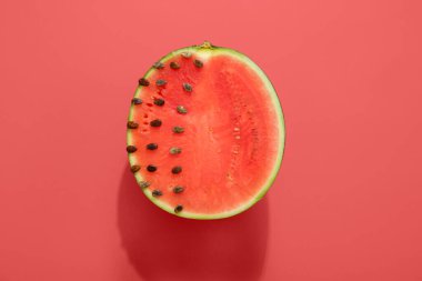 Kırmızı zemin üzerinde tohumları olan olgun karpuzun yarısı.