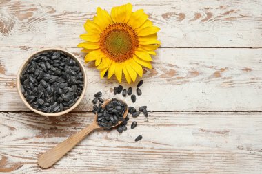 Beyaz ahşap arka planda tohumları olan güzel ayçiçeği ve kase