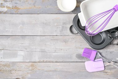 Mutfak gereçleri ve yemek tabağı beyaz ahşap masada.