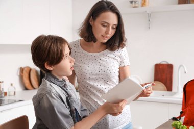 Anne, küçük oğluna mutfakta ödevlerinde yardım ediyor.