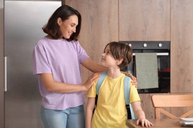 Anne oğlunu mutfakta okula hazırlıyor.