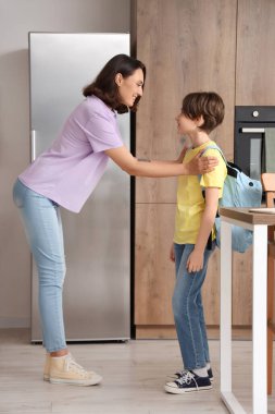 Anne oğlunu mutfakta okula hazırlıyor.