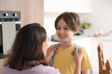 Anne oğlunu mutfakta okula hazırlıyor.