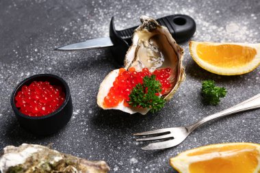 Limonlu lezzetli istiridye ve gri arka planda kırmızı havyar.