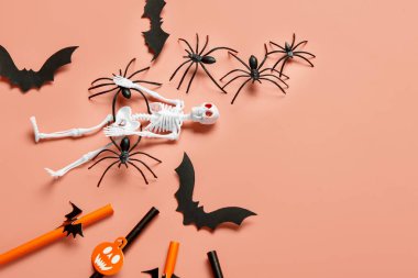 İskelet, kamış, kağıt yarasa ve örümcekli kompozisyon Cadılar Bayramı kutlamaları için mercan arka planda, yakın plan