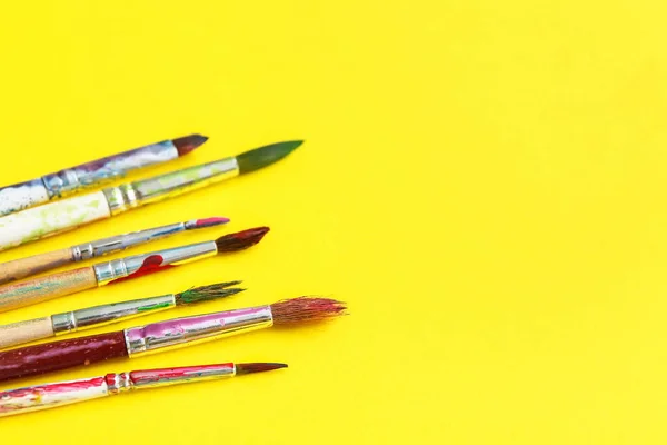 Artist\'s brushes with paints on yellow background
