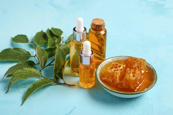 Flaschen Kosmetiköl Mit Honig Und Blättern Auf Blauem Hintergrund — Stockfoto
