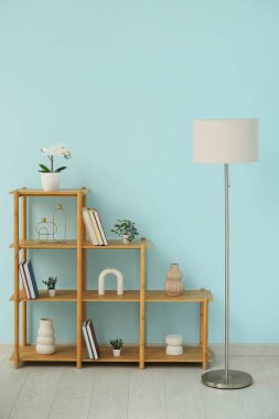 Kitapları, dekorasyonu ve lambası olan raf odası mavi duvarın yanında.
