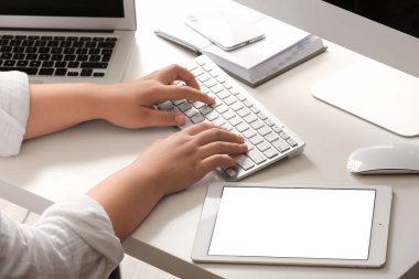 Ofisinde klavye ve tablet bilgisayarla çalışan kadın programcı, yakın plan