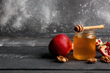 Rosh Hashanah kutlaması için nar ve elmalı bal kavanozu (Yahudi Yeni Yılı) siyah ahşap masada.