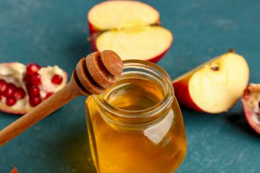 Mavi arka planda Rosh Hashanah kutlaması (Yahudi Yeni Yılı) için nar ve elmalı bal kavanozu