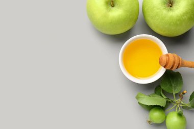 Rosh Hashanah kutlamaları (Yahudi Yeni Yılı) için gri arkaplanda bir kase bal ve elma