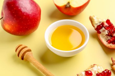 Sarı zemin üzerinde Rosh Hashanah kutlaması (Yahudi Yeni Yılı) için bir kase nar ve elmalı bal.