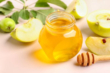 Rosh Hashanah 'ın yeni yıl kutlamaları için pembe arka planda bir kavanoz bal ve elma.