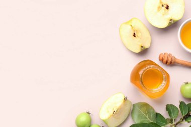 Rosh Hashanah 'ın yeni yıl kutlamaları için pembe arka planda bir kavanoz bal ve elma.