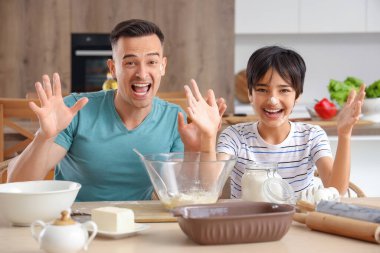 Küçük çocuk ve babası mutfakta yemek yaparken eğleniyorlar.