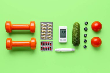 Kalemli glukometre, haplar, dambıllar ve yeşil arka planda yiyecekler. Diyabet kavramı